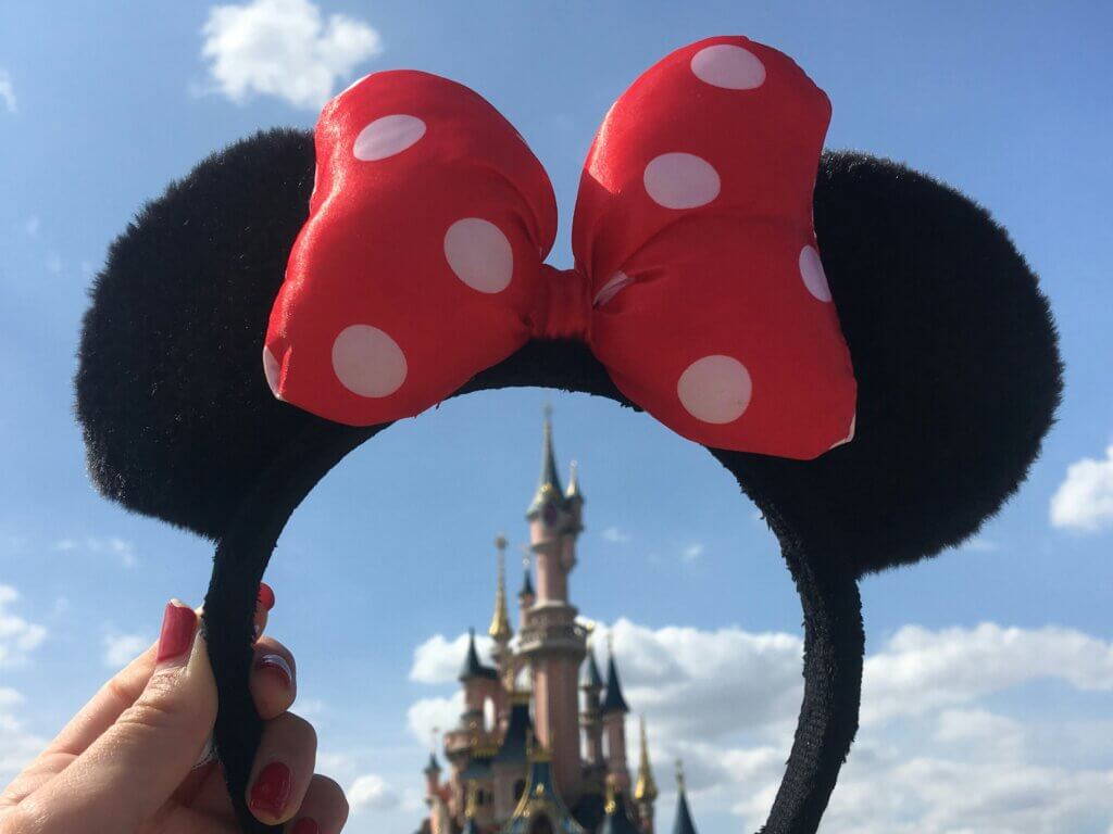 a person holding up a mouse ears headband in their Disney trip